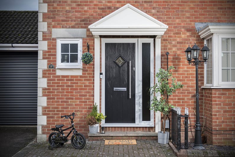 black composite front entrance door on modern home with glass side panel